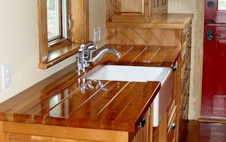 Cherry face grain countertop with an integrated sloping drainboard on each side of a farm sink.