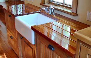 Cherry face grain countertop with an integrated sloping drainboard on each side of a farm sink.