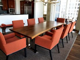 Custom dining table using walnut slabs with wane edges on a custom handmade mirror polished bronze base.