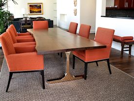 Custom dining table using walnut slabs with wane edges on a custom handmade mirror polished bronze base.