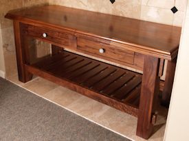 Custom walnut table with false drawer fronts and slat style shelf.