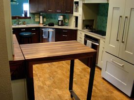 Custom rolling walnut table with partial returns with a mitre joint on a flat metal base.  With a custom matching drawer cabinet.