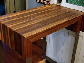 Custom rolling walnut table with partial returns with a mitre joint on a flat metal base.  With a custom matching drawer cabinet.