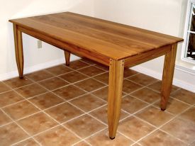 Custom face grain shaker style dining table with hand carved aprons and walnut accents on legs.