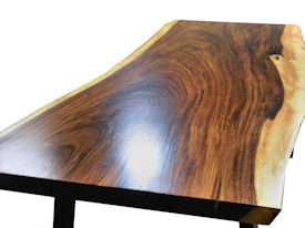 Custom dining table using a Guanacaste Slab Top with Natural Edges and Waterlox Satin finish.  Custom flat black metal base.