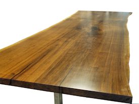 Custom dining table using walnut slabs with wane edges on a custom handmade mirror polished bronze base.