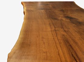 Custom dining table using walnut slabs with wane edges on a custom handmade mirror polished bronze base.