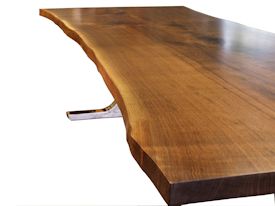 Custom dining table using walnut slabs with wane edges on a custom handmade mirror polished bronze base.