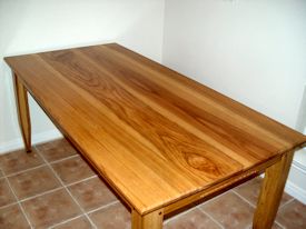 Custom face grain shaker style dining table with hand carved aprons and walnut accents on legs.